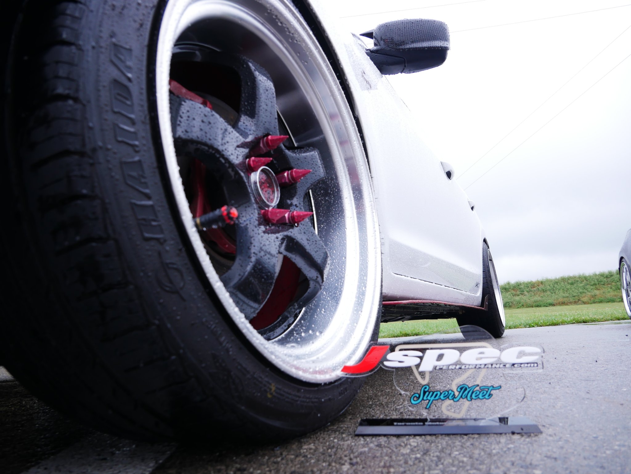 Custom black and polished Acura wheel with red spike lug nuts and red brake caliper