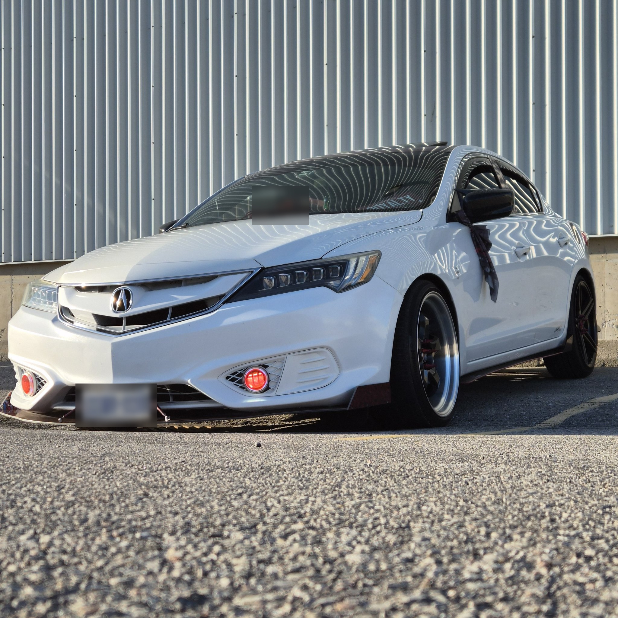 White Acura with its red-splatter custom front lip in daylight