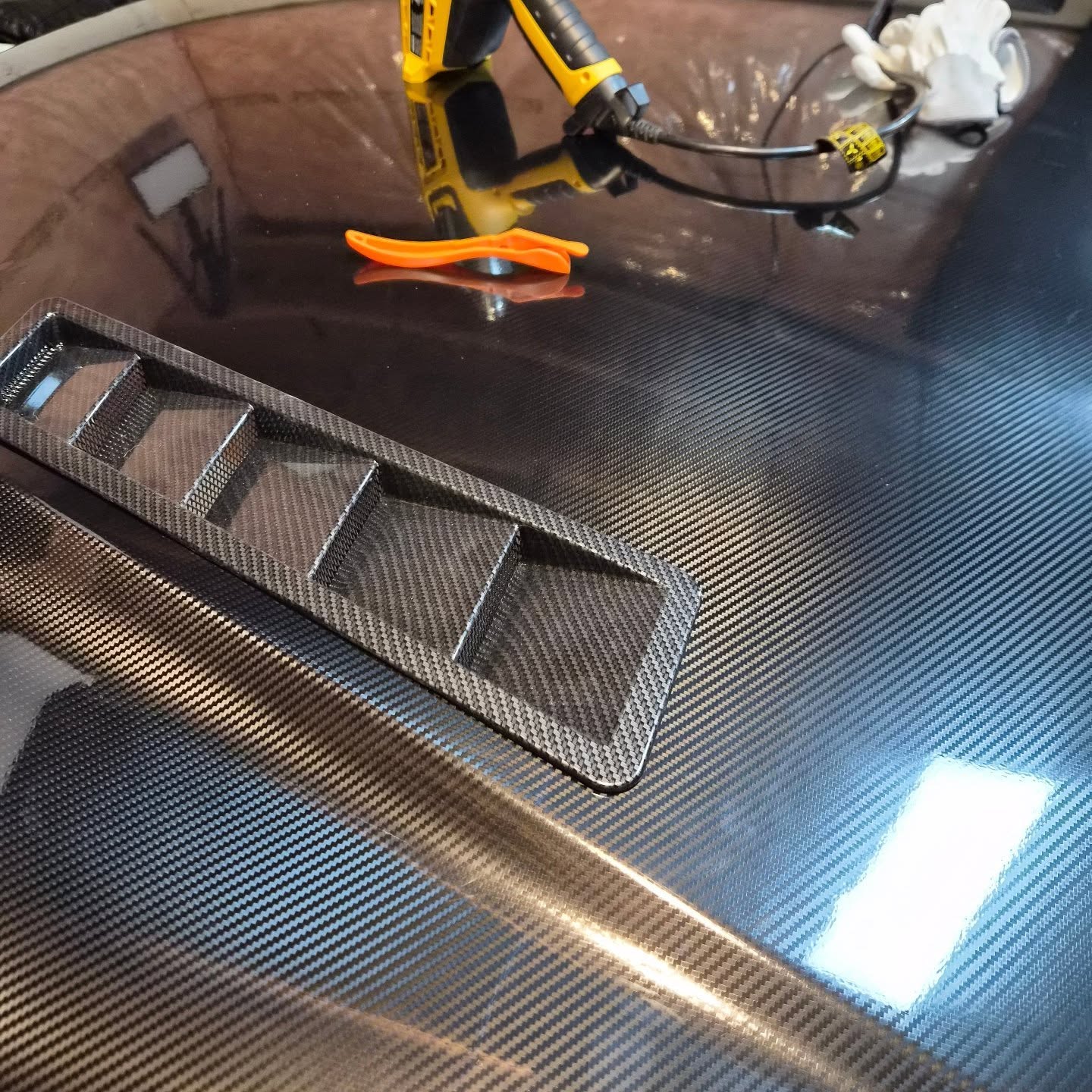 Carbon-pattern hood surface with vent trim during installation