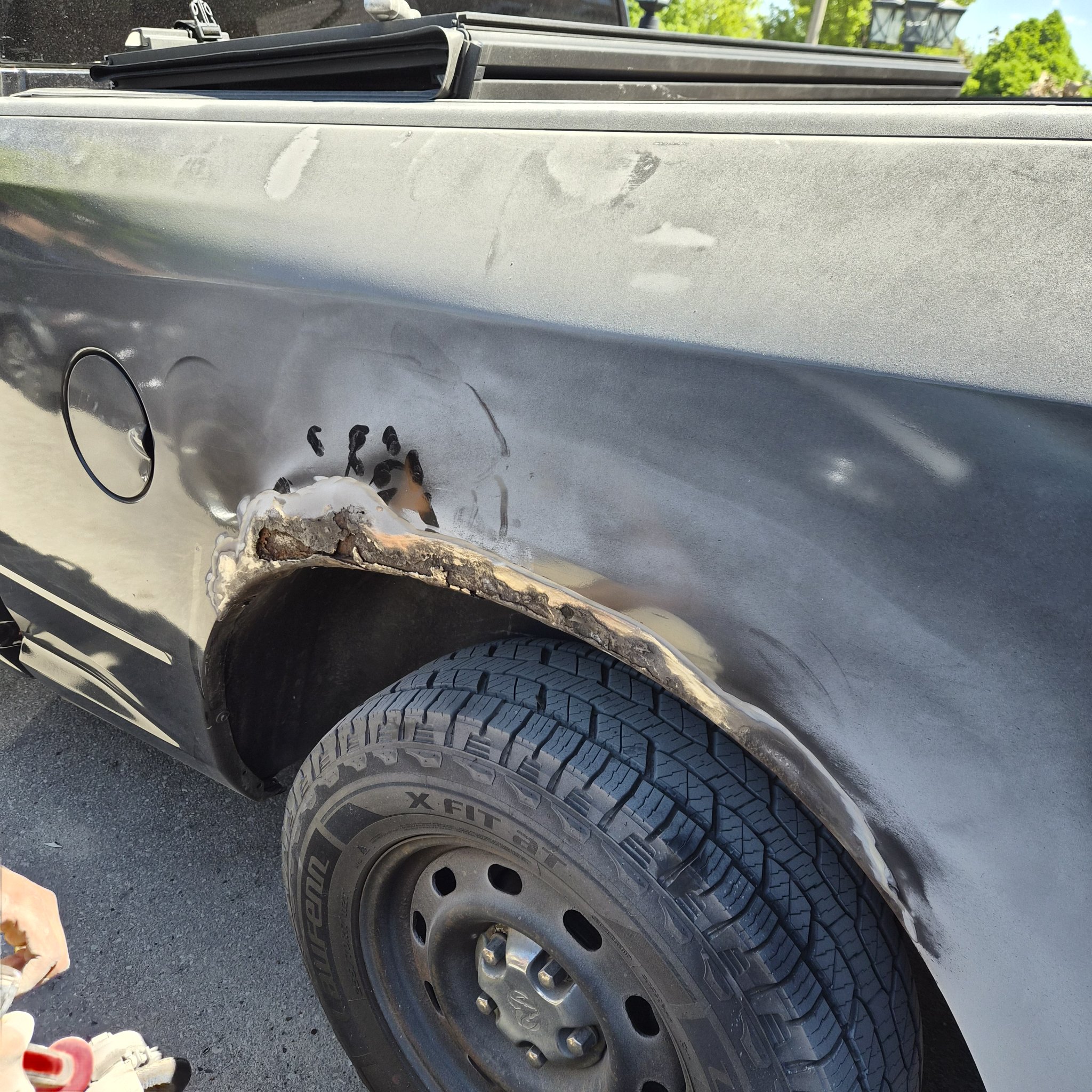 Ram wheel arch stripped while a grinder prepares the corroded metal