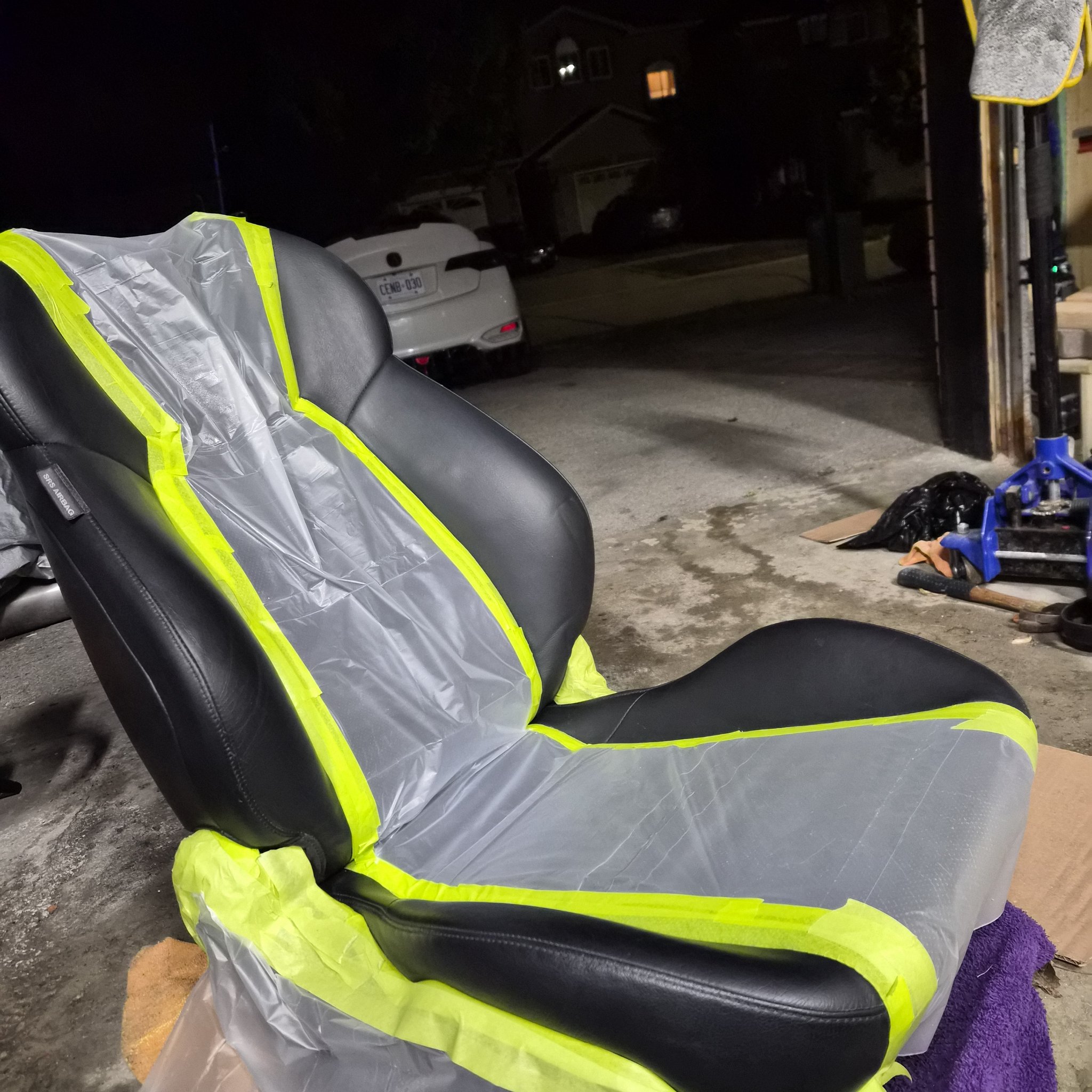 Leather seat masked with plastic and yellow tape during preparation