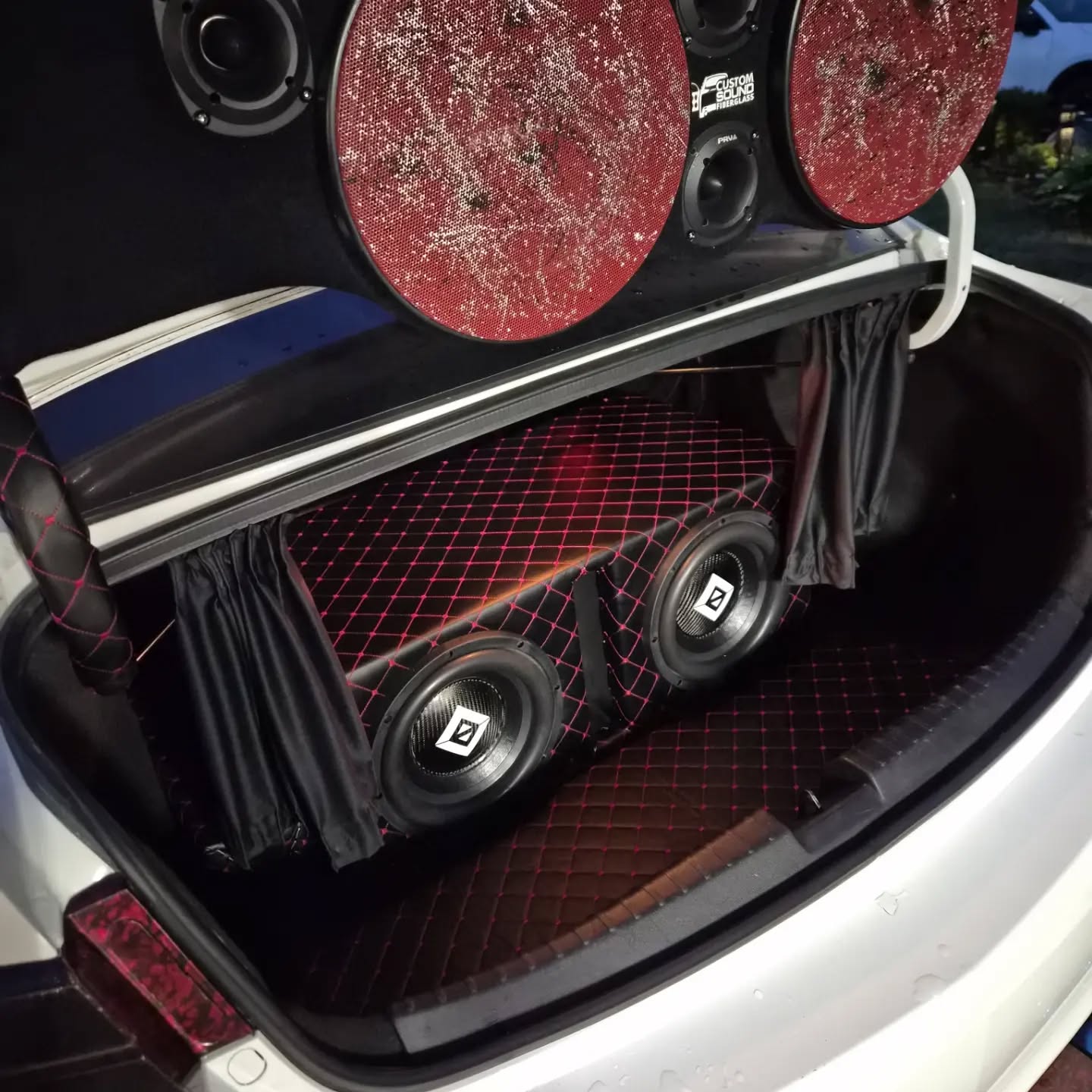 Custom trunk audio build with black upholstery and red diamond stitching